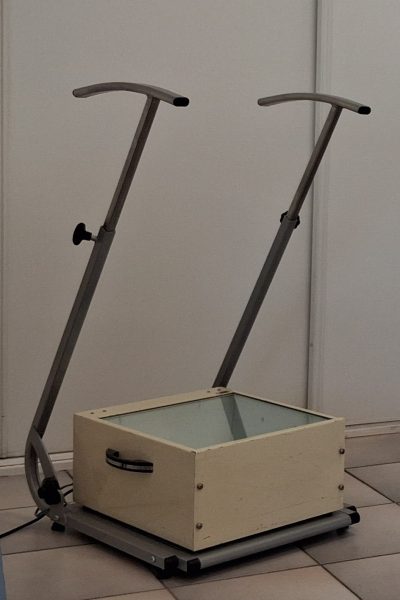 Appareil d'examen : Le podoscope. Il s'agit d'une boîte dont le dessus est faite d'une vitre sur laquelle le patient se tient debout et permettant de voir la face plantaire de ses pieds.